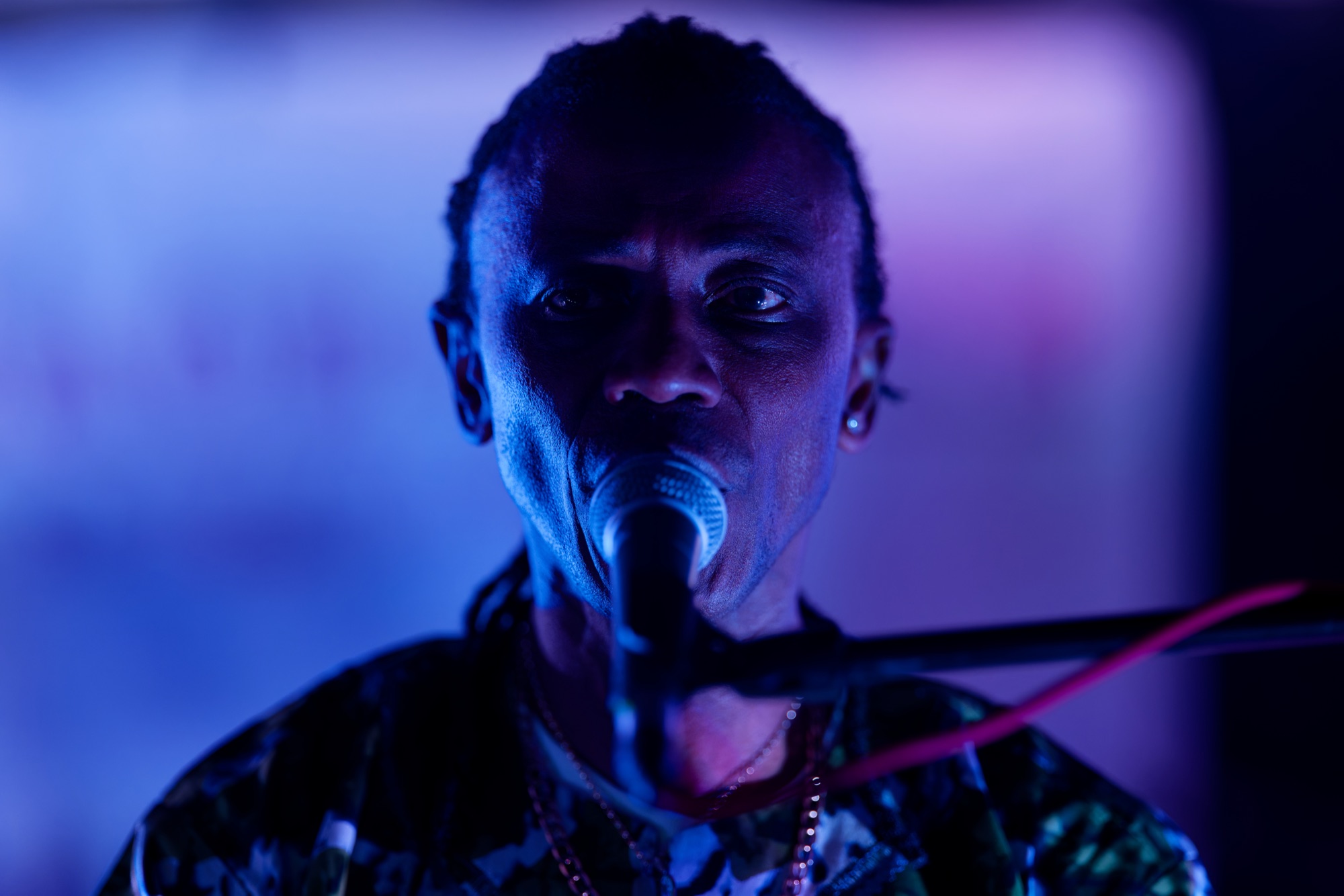 Singer performing in close-up with blue and purple stage lighting